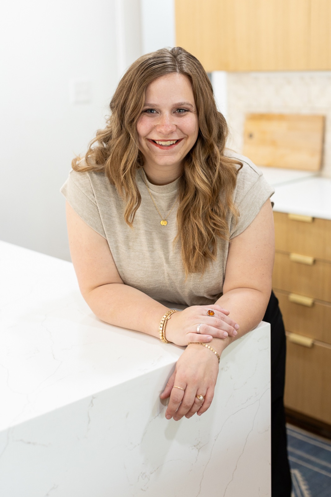 Marisa Grover smiling, leaning on a white kitchen island in one of her rental properties