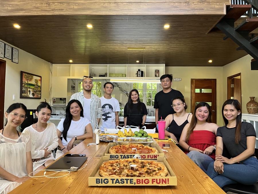 SimplyVA team gathered around a long table with pizza and fruit