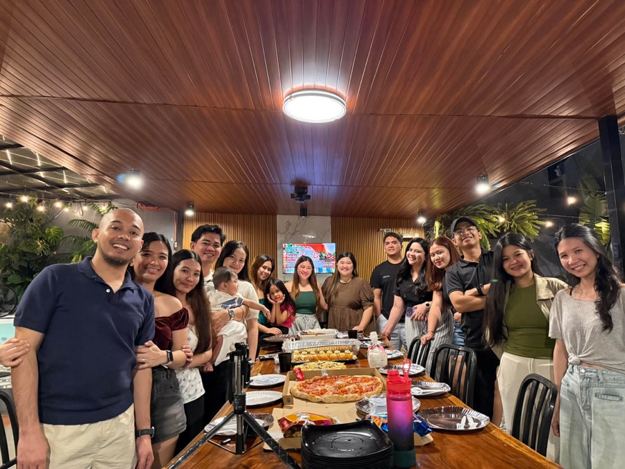 SimplyVA virtual assistants sharing pizza at a long table under string lights