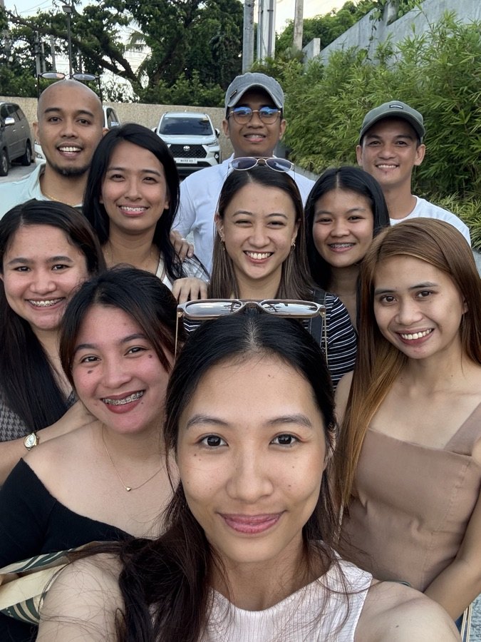 A big group selfie of smiling SimplyVA virtual assistants outdoors
